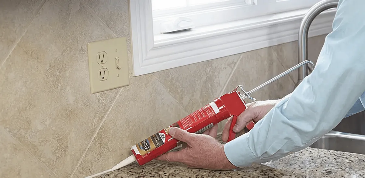 Handyman applying caulk along a kitchen backsplash and countertop seam in Boulder, CO