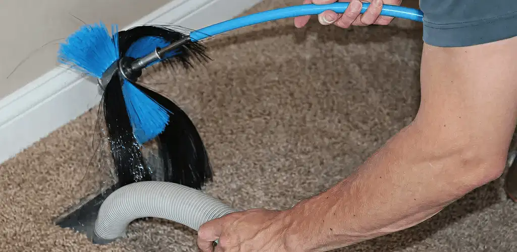 Dryer vent cleaning technician brushing lint from a vent line in Boulder, CO