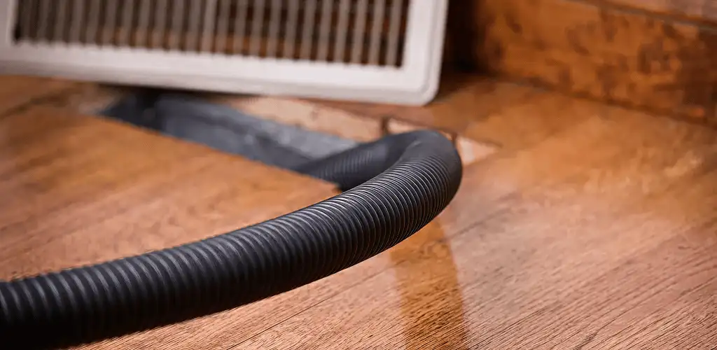 Air duct cleaning hose inserted into a floor vent for ductwork cleaning in Boulder, CO