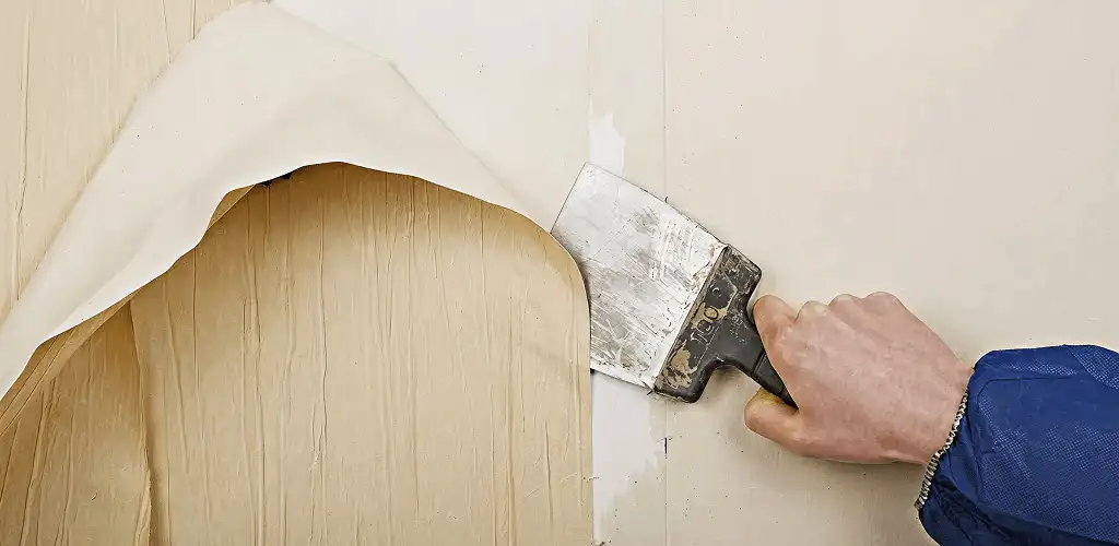 Handyman removing wallpaper with a scraper for wall preparation in Boulder, CO