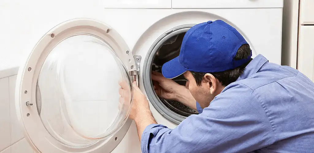 Washing machine repair handyman inspecting a front-load washer drum in Boulder, CO