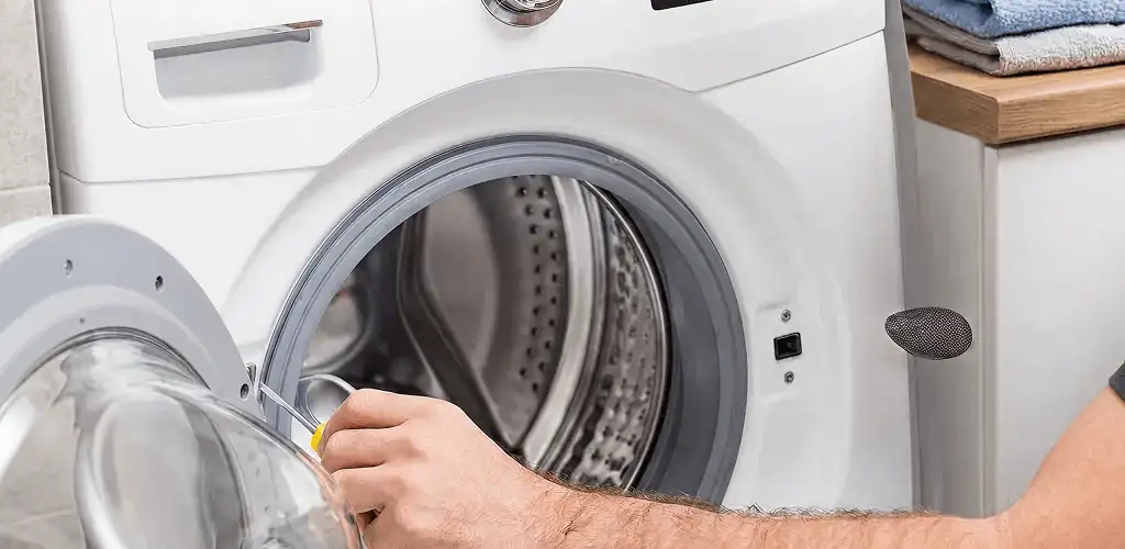 Handyman repairing a front-load washing machine and inspecting the drum in Boulder, CO